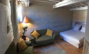 Una habitación acogedora con un sofá verde, una cama, una lámpara y una planta en maceta.
