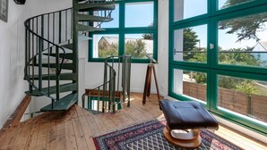 A spiral staircase, a large window with a view, and a patterned rug.