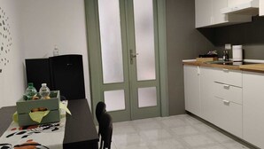 Cocina compacta con zona de comedor, que incluye un refrigerador, un lavamanos y una encimera con una tetera.