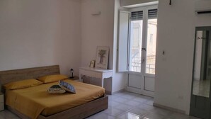 Un dormitorio con cama, mesita de noche y ventana con vista a un balcón.