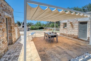 A stone building with a covered patio, outdoor seating, and a stone oven. - Trullo 'Pietra800' with Private Terrace, Private Garden and Air Conditioning (Mesagne)