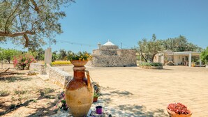 Une cour avec un bâtiment en pierre, un grand vase et des plantes en pot.