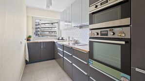 Una cucina moderna con mobili grigi, un forno in acciaio inossidabile e una finestra con vista su un quartiere residenziale.