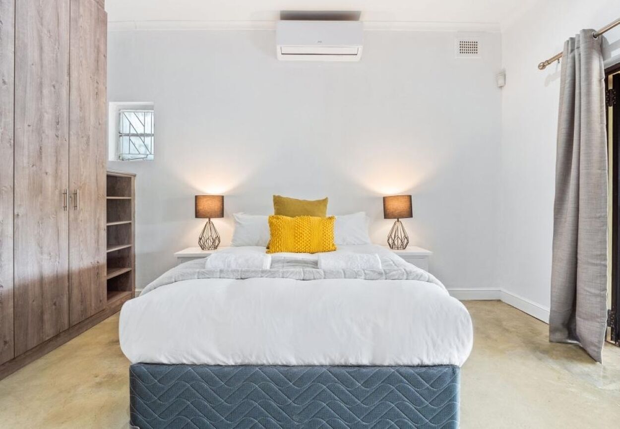 A bedroom with a bed, bedside lamps, a window, and a wardrobe.