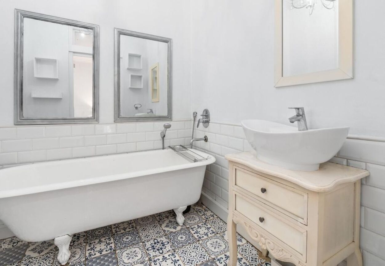 Ein Badezimmer mit einer weißen Badewanne, einem Waschbecken mit weißer Schale und zwei Spiegeln.