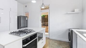Una cocina moderna con armarios blancos, estufa a gas, horno, refrigerador y lavadora.