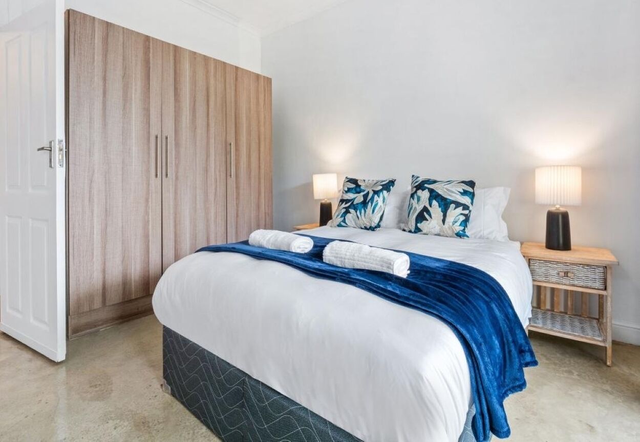 A bedroom with a bed, two bedside tables, a wardrobe, and a nightstand.