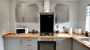 Una cocina compacta con armarios grises, un microondas, una estufa, un tostador y un lavabo.