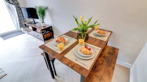 Una mesa de comedor con platos de croissants y fresas, un jarrón con flores amarillas y un vaso de zumo de naranja.