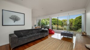 Ein modernes Wohnzimmer mit einem grauen Sofa, einem roten Sitzsack und einem Holzboden.