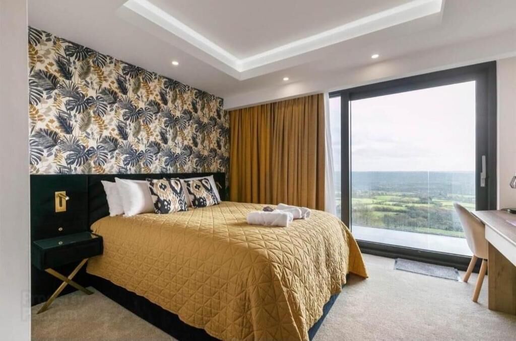Een moderne hotelkamer met een groot bed, een bureau en uitzicht op het landschap.