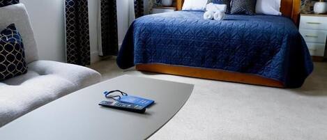 A hotel room with a bed, a chair, a table, and a window.
