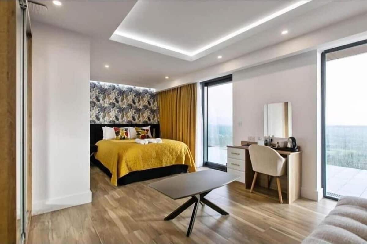 Una habitación de hotel moderna con cama, escritorio y un amplio ventanal.