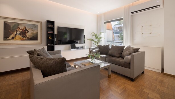 A modern living room with a sofa, a coffee table, a flat-screen TV, and a painting on the wall. - Nikita 1 3rd·Signature Athenian Residence (Athens)