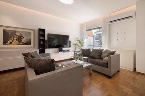 A modern living room with a sofa, a coffee table, a flat-screen TV, and a painting on the wall. - Nikita 1 3rd·Signature Athenian Residence (Athens)
