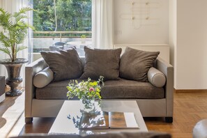 Een moderne woonkamer met een bank, een salontafel en een potplant.