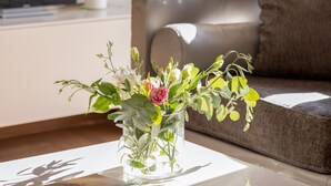 A living room with a sofa, a coffee table with a vase of flowers, and a television on the wall. - Nikita 1 3rd·Signature Athenian Residence (Athens)