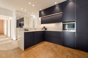 A modern kitchen with dark cabinetry, a built-in oven, and a large mirror. - Nikita 1 3rd·Signature Athenian Residence (Athens)