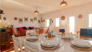 A dining area with white chairs, a table set for four, and a bottle of water.