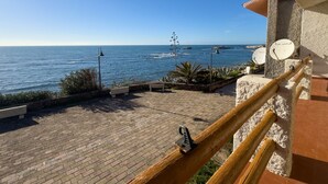 A coastal view from a balcony with a brick floor, a wooden railing, and a satellite dish.