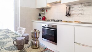 A compact kitchen with white cabinets, a gas stove, an oven, and a coffee maker on the counter.