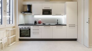 A modern kitchen with white cabinetry, a built-in oven, a microwave, and a gas stove. - Palazzo Accademia-brunelleschi-1 (Florence)