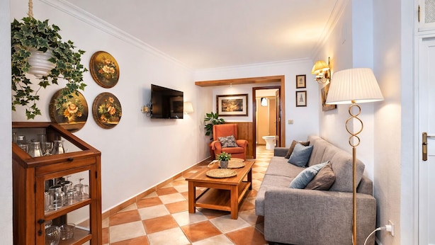 Una sala de estar con un sofá, una mesa de centro, un televisor y una lámpara.