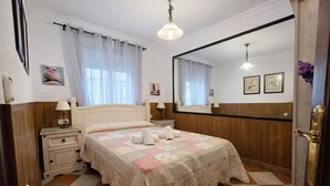 Un dormitorio con cama, mesitas de noche, un espejo y suelo a cuadros.