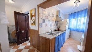 Una cocina con isla de madera, salpicadero de azulejos y ventana con cortinas azules.