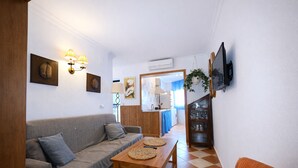 Una sala de estar acogedora con un sofá, una mesa de madera y una cocina al fondo.