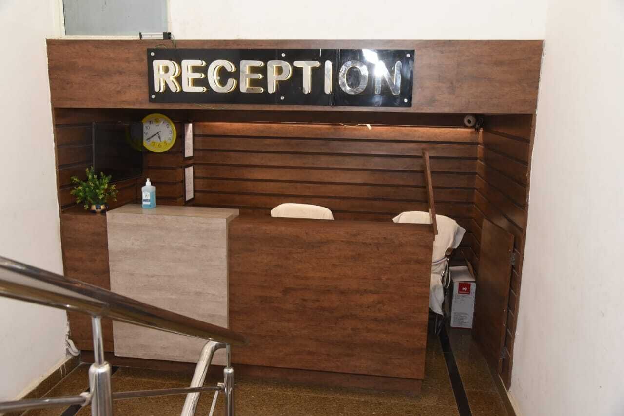 A reception desk with a sign that reads "RECEPTION" above it. There is a clock on the wall to the left of the desk.