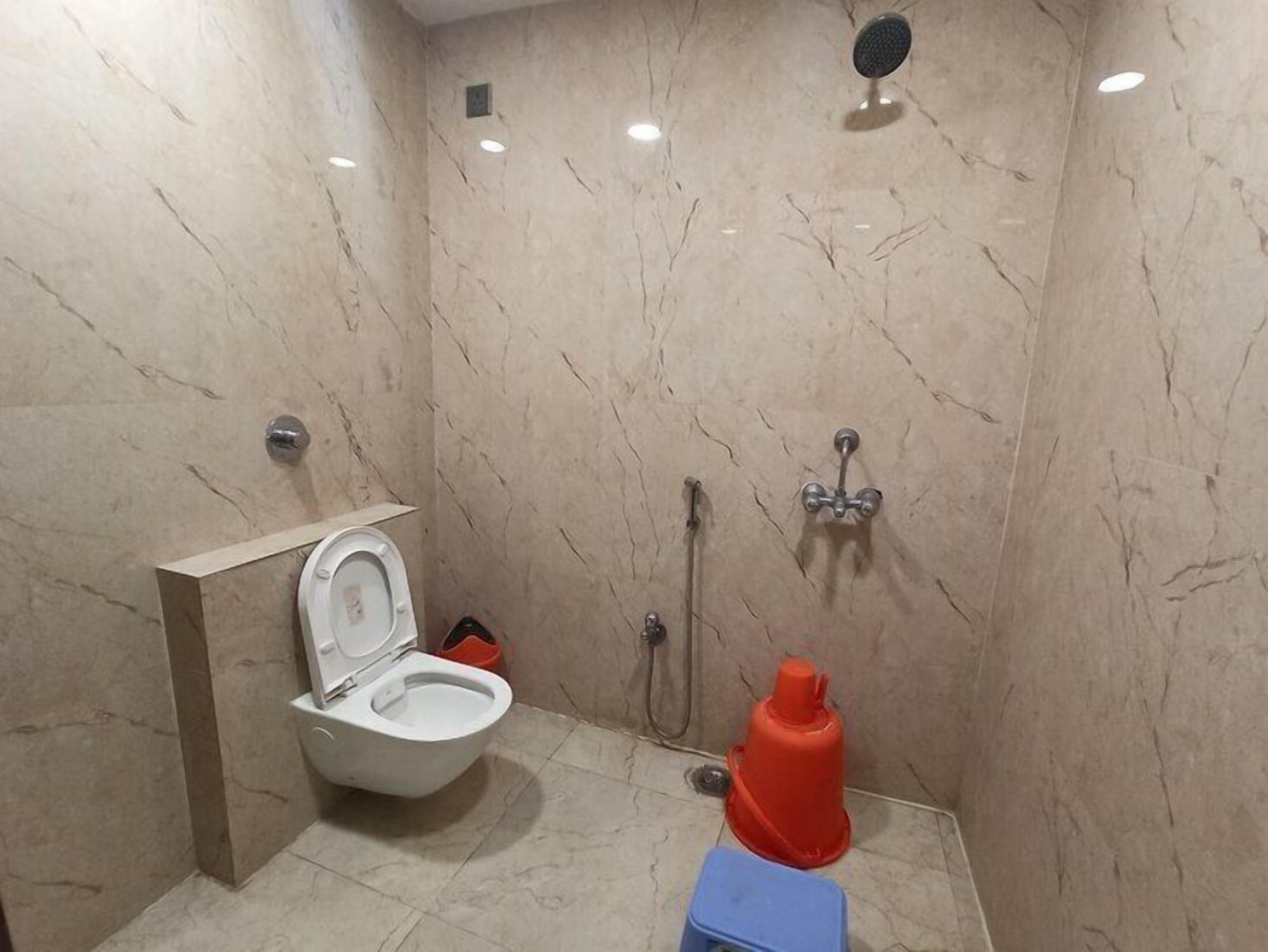 Ein Badezimmer mit Toilette, Dusche und einem roten Gegenstand auf dem Boden.