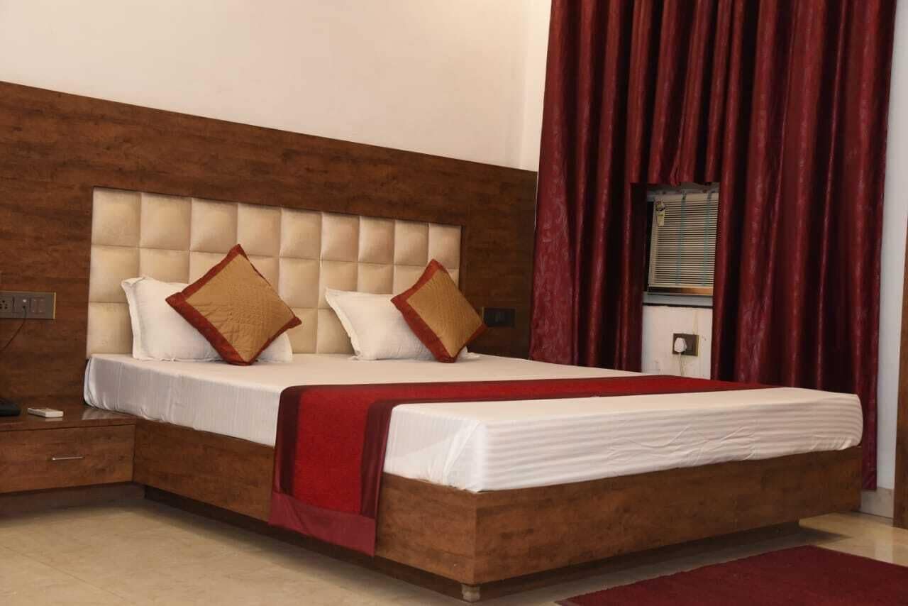 Ein ordentlich bezogenes Bett mit einem Holzkopfteil, einer roten Tagesdecke und zwei Zierkissen.