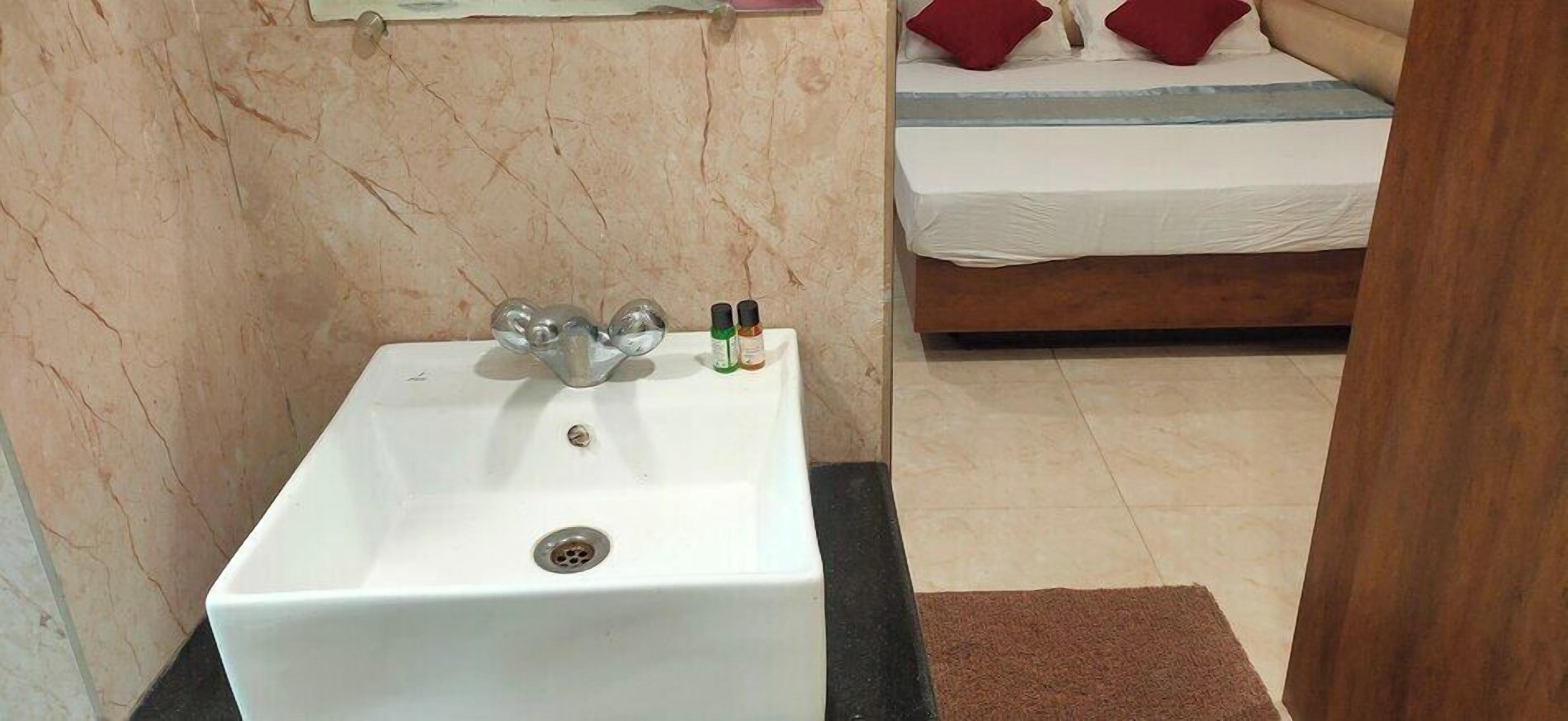 A bathroom with a white sink, a mirror, and two bottles of toiletries on the counter.