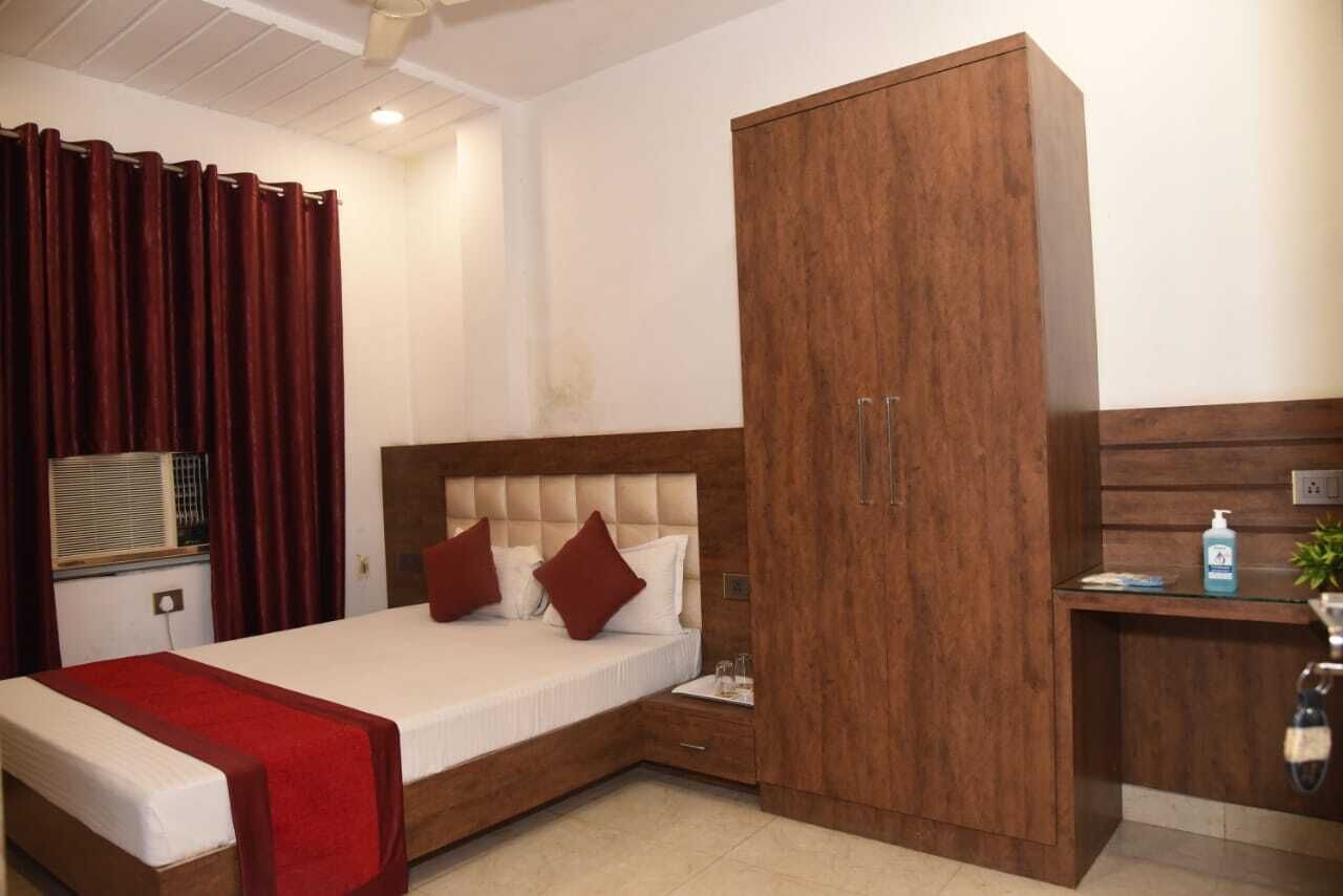 A bedroom with a bed, a wooden wardrobe, a bedside table, and a red curtain.