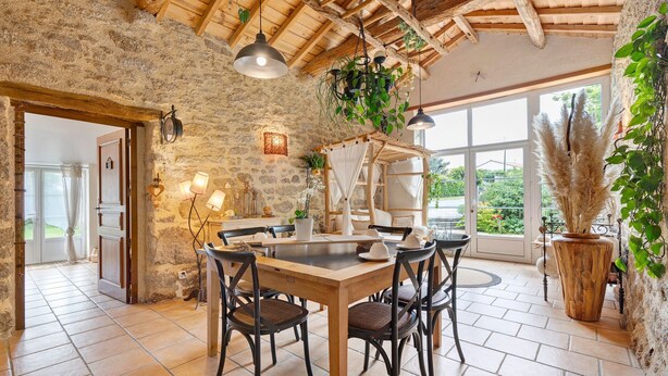 A rustic dining area with a stone wall, wooden ceiling, and large windows. - Bed and Breakfast 'Chambre Nature' with Shared Garden and Wi-Fi (Saint-Malô-du-Bois)