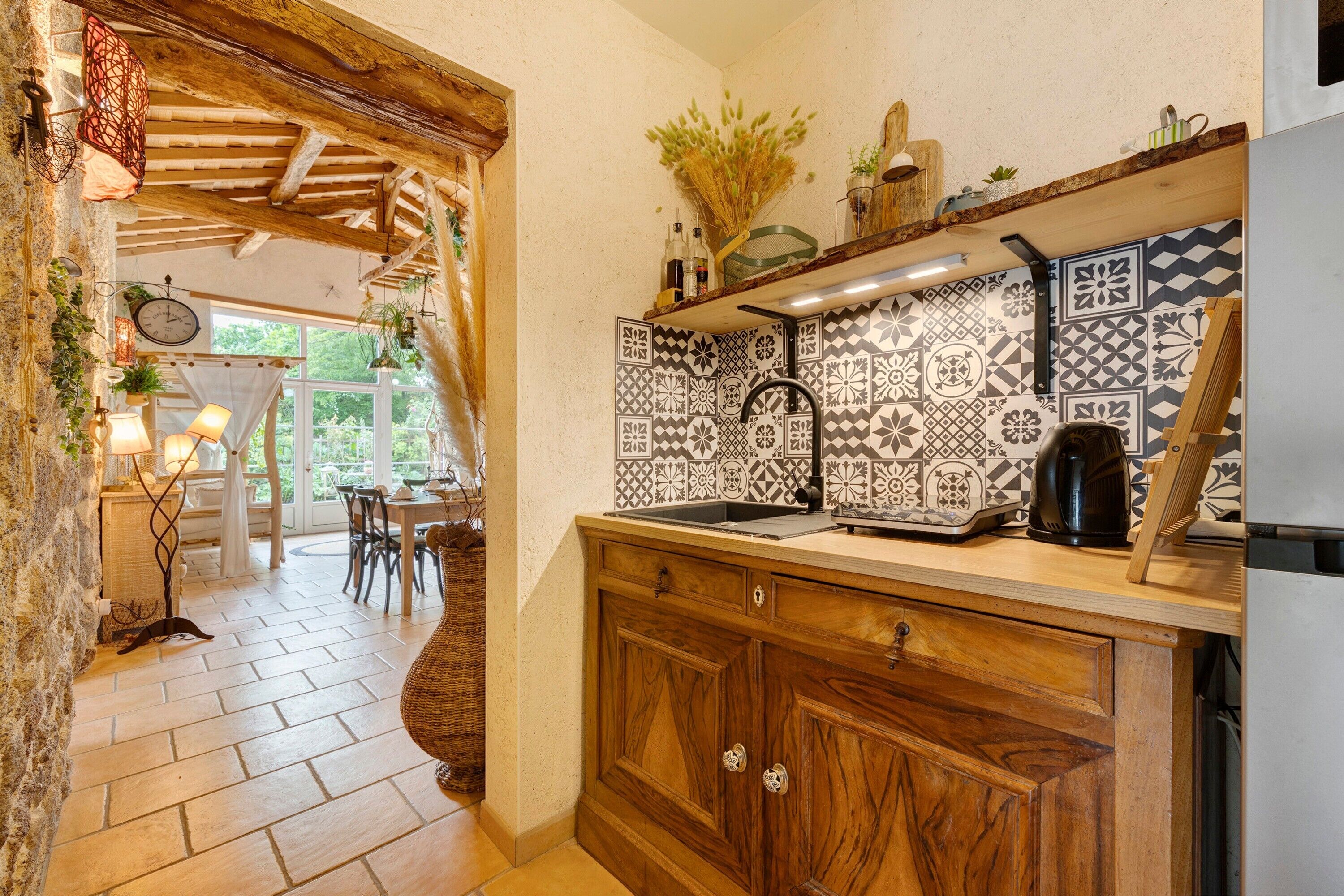 Une cuisine avec des carreaux décoratifs, des armoires en bois et un plafond rustique.