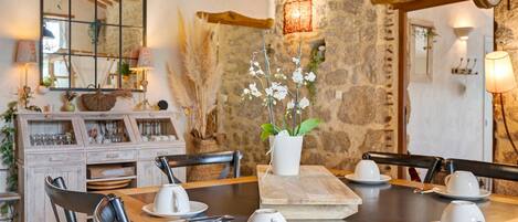 A rustic dining area with a stone wall, wooden table, and chairs.