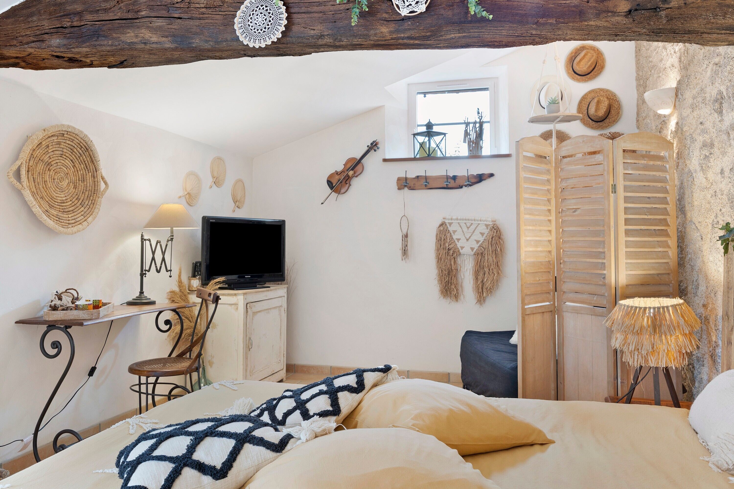 Un dormitorio con cama, escritorio, televisor y ventana.