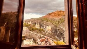 Ένα παράθυρο με θέα σε ένα ορεινό τοπίο και ένα κτίριο.