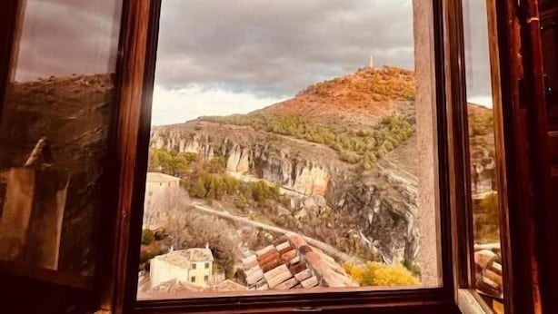 Une fenêtre donnant sur un paysage montagneux et un bâtiment.