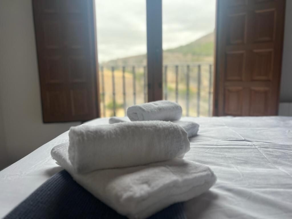 A bed with neatly folded white towels and a view of a balcony with closed doors.