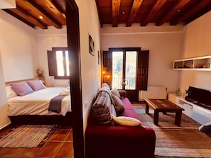 A cozy room with a bed, a sofa, a television, and a window with a view. - Apartamentos Rascacielos San Martin (Cuenca)