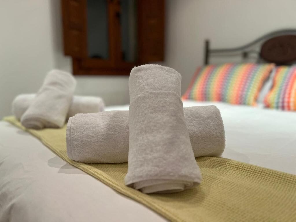 Un letto rifatto con lenzuola bianche e un cuscino a righe colorate.