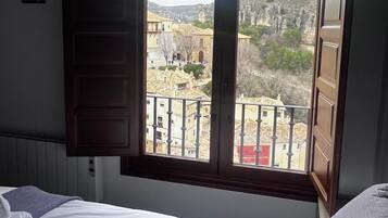 A bedroom with a large window overlooking a town and a mountainous landscape.