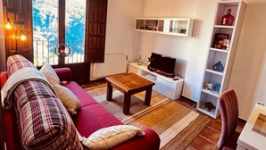Un salon chaleureux avec un canapé rouge, une table basse en bois et une bibliothèque.
