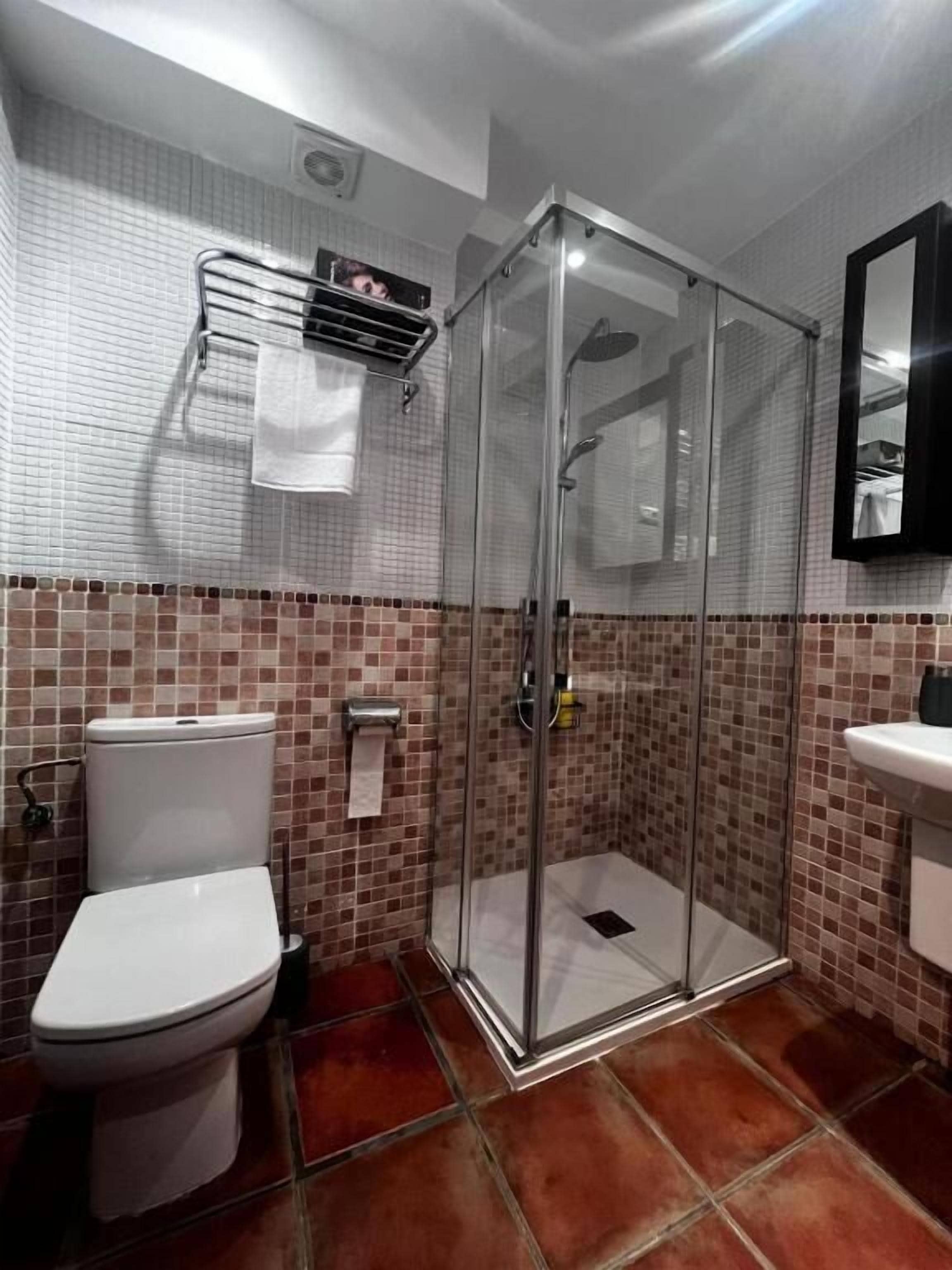 A bathroom with a glass-enclosed shower, a toilet, and a sink.