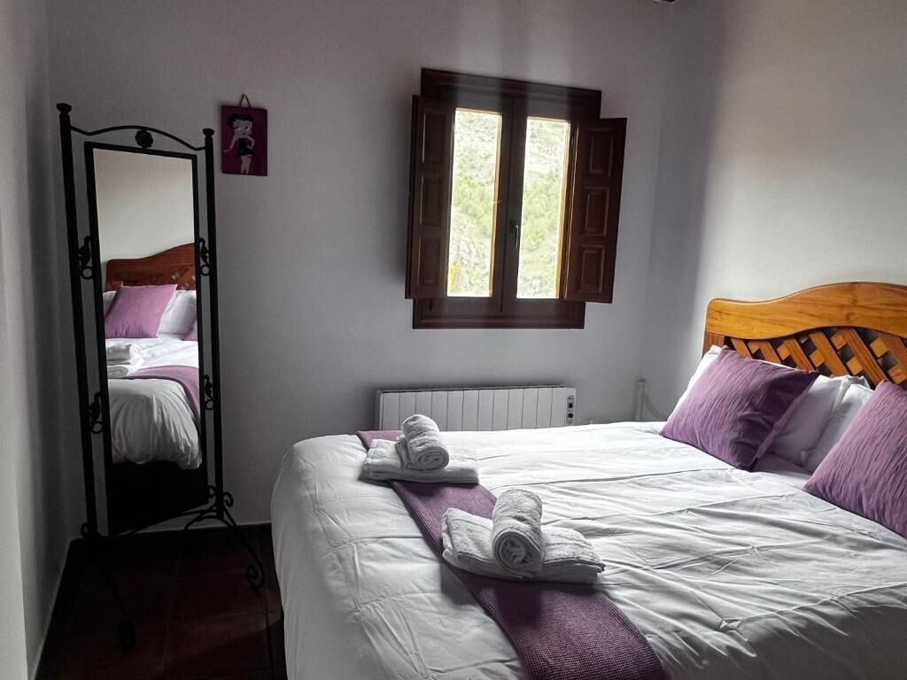 A bedroom with a bed, a window, a radiator, and a mirror.