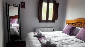 A bedroom with a bed, a window, a radiator, and a mirror.