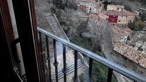 Un balcon offrant une vue sur une ville historique, avec ses bâtiments et une colline rocheuse.